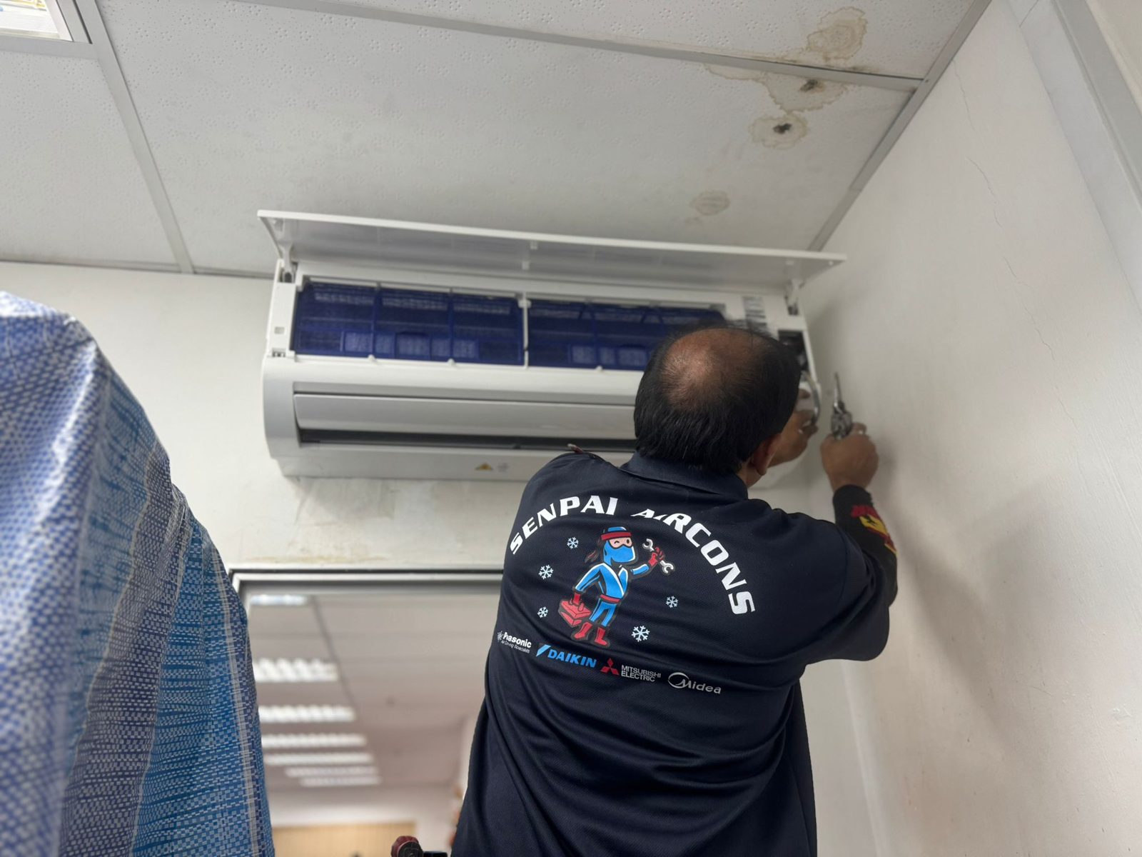 Servicing an open wall unit with a sheet hung to catch drips