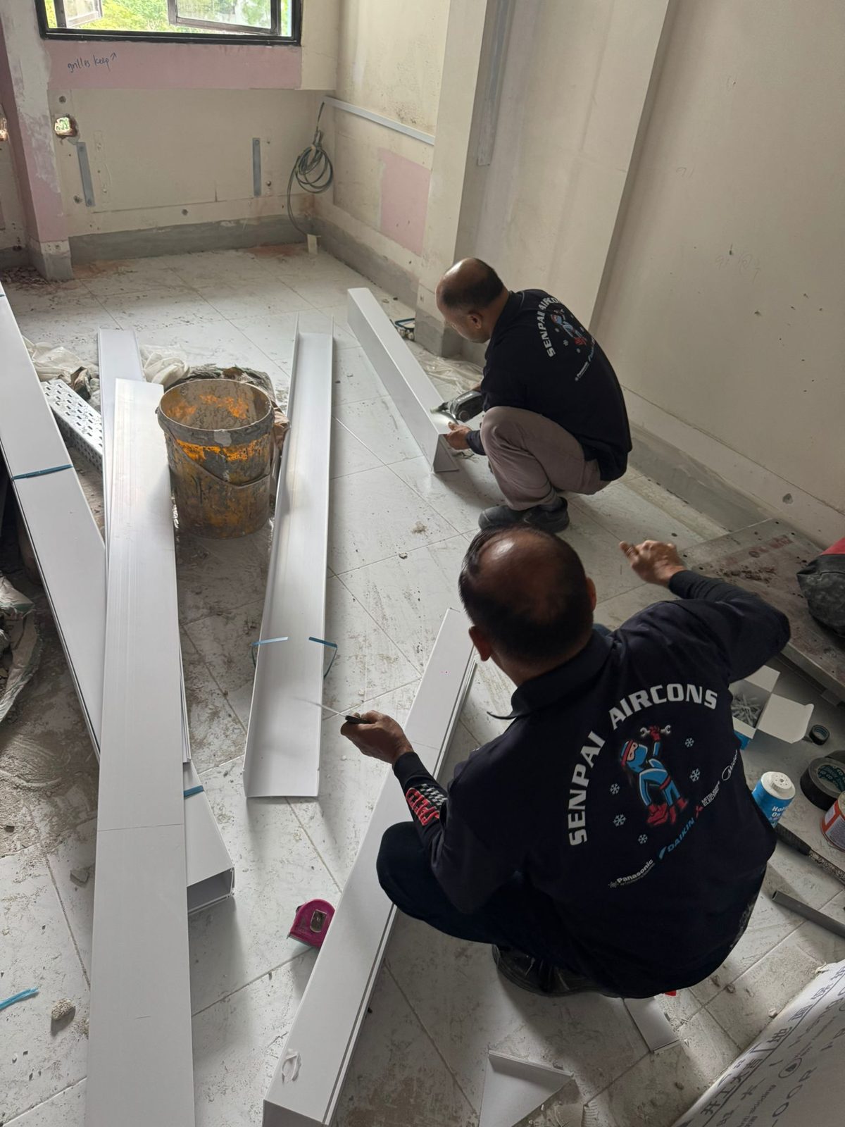Two Senpai fitters cutting trunking on a new installation